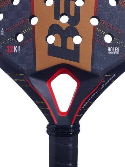 Eine Detailansicht des Babolat Technical Viper 2024 Padelschlägers hebt seine aufwendig gemusterte Oberfläche mit strategisch platzierten Perforationen hervor. Die Begriffe „12K Carbon“, „Holes Pattern System“ und das ikonische „Babolat“-Logo sind deutlich sichtbar. Dieser Schläger verfügt über einen schwarzen Griff und eine auffällige Farbpalette aus Rot und Orange, die für hohe Leistungsfähigkeit steht.