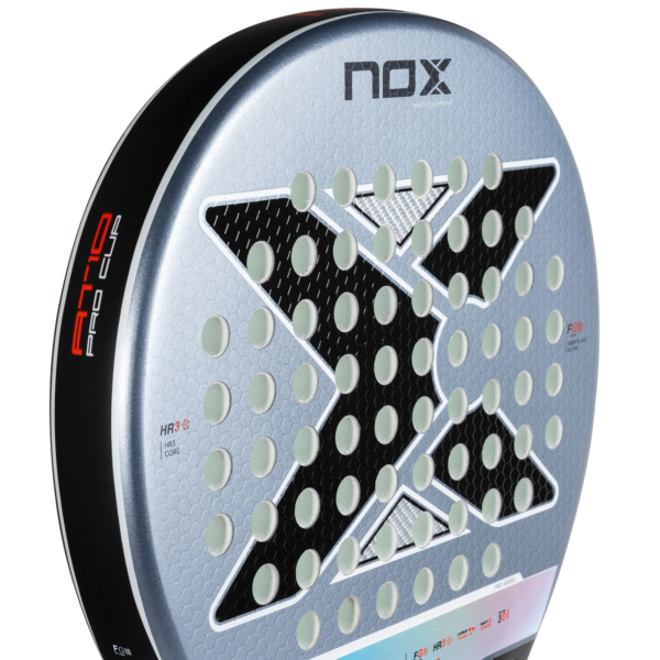 Nahaufnahme eines NOX AT10 Pro Cup Comfort 2025 Padelschlägers mit runder Form, perforiertem Muster und markantem schwarzen „X“-Design. Der Modellname ist auf der Seite sichtbar, während die Oberfläche eine strukturierte, wabenartige Optik aufweist.