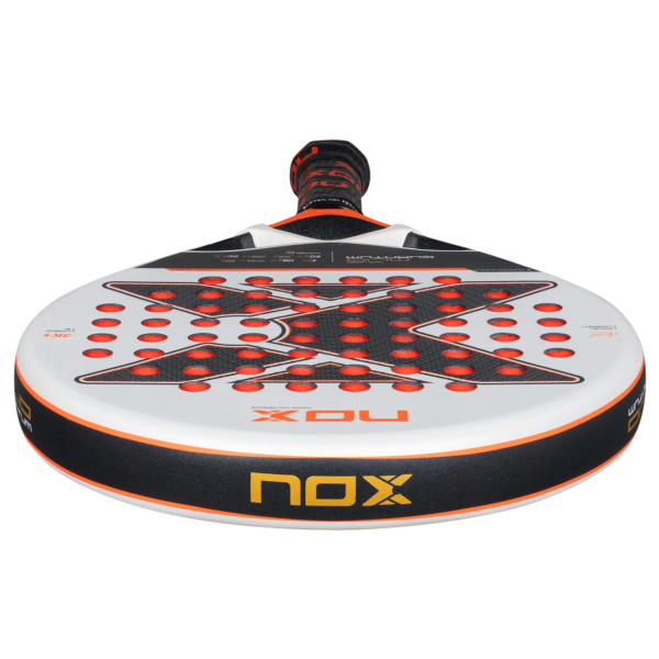 Eine Nahaufnahme des NOX ML10 QUANTUM 3K Miguel Lamperti Padelschlägers mit einem schwarz-orangefarbenen Design auf weißer Oberfläche. Der Markenname „Nox“ ist sowohl auf dem Griff als auch auf der Vorderseite sichtbar und wird durch rote, kreisförmige Löcher hervorgehoben, die über die Oberfläche verteilt sind.